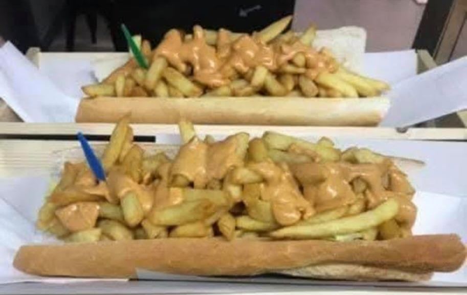 Frites nappées de sauce servies avec une demi-baguette